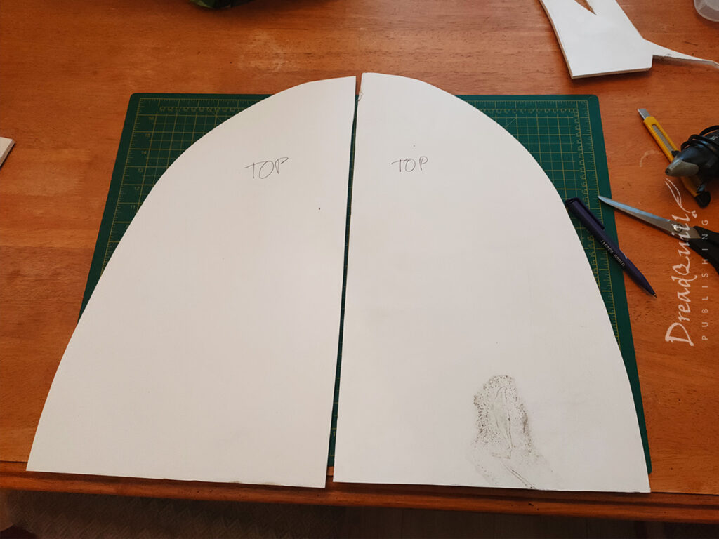 Two hemicircular pieces of foamboard roughly A2 size with the word 'top' written on each