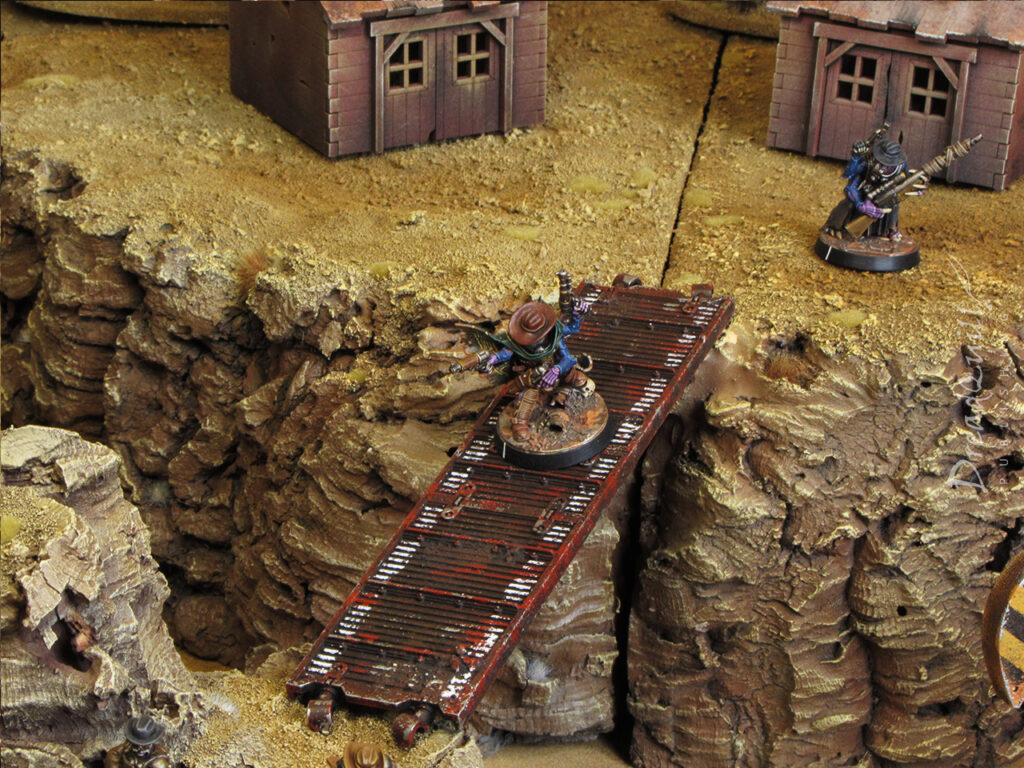 ash waste modular hills with a metal platform spanning a chasm and a genestealer cultist cowboy crossing it